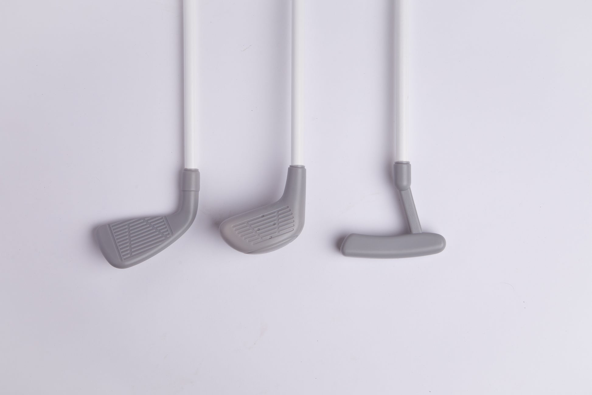 Toddler golf club heads, driver, putter, and iron, on white shafts