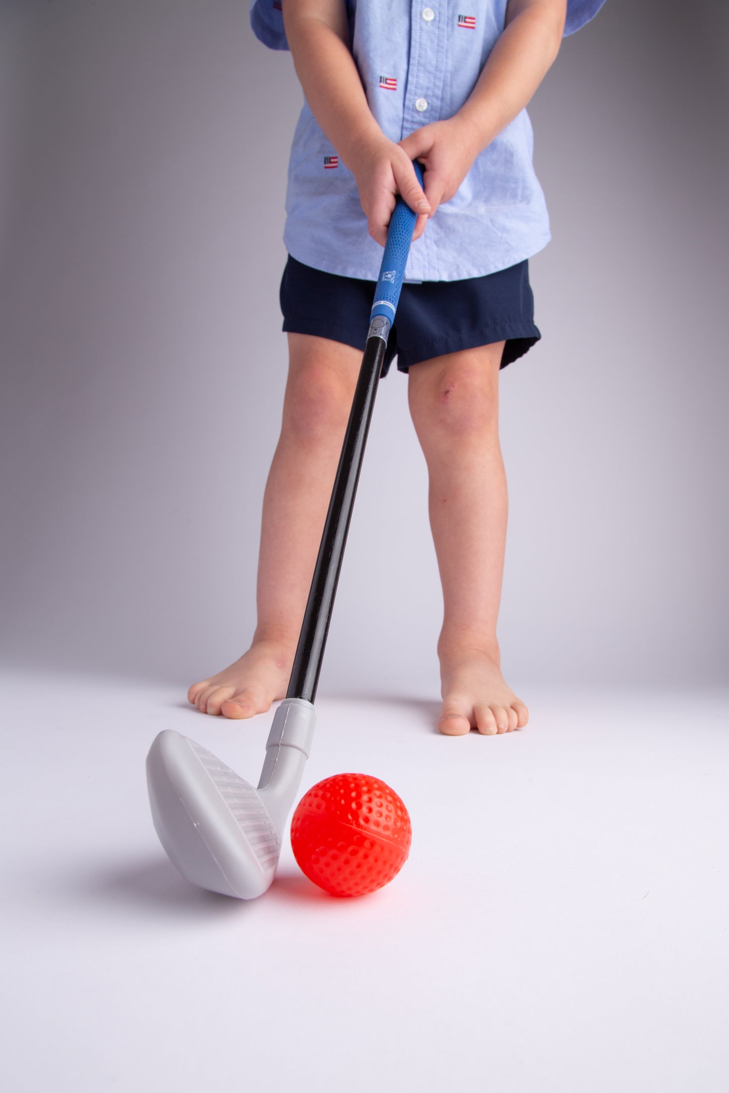 Toddler swinging lightweight iron golf club with real blue grips
